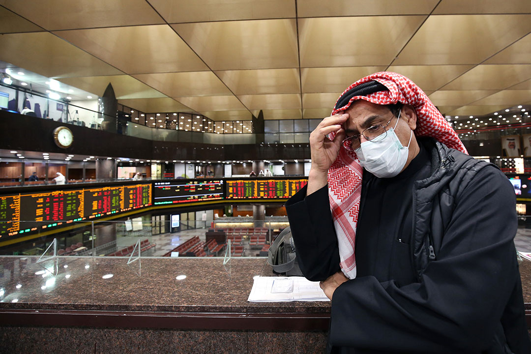 Een handelaar op de Boursa Kuwait in Koeweit draagt een mondkapje tegen het coronavirus. - Foto: AFP
