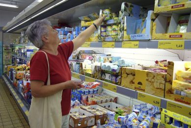 Een vrouw pakt zuivel uit het schap van een Aldi in  München. Na eerdere flinke prijsstijgingen verlaagt Aldi de prijzen van biologische melk nu weer. - Foto: ANP